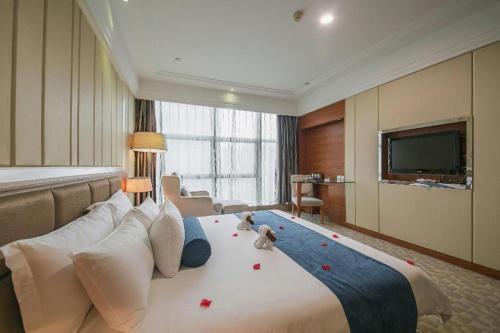 a large bed in a hotel room with a television at Ningbo East Shipu Hotel in Ningbo