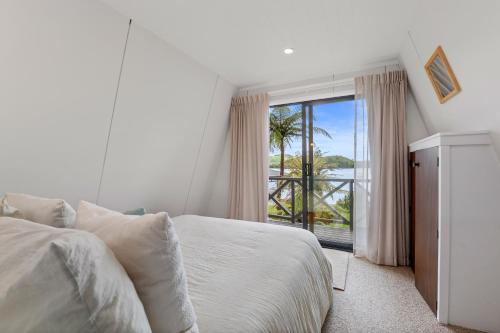 a white bedroom with a bed and a large window at Okawa Bay Lakeside - Lake Rotoiti A-Frame in Mourea