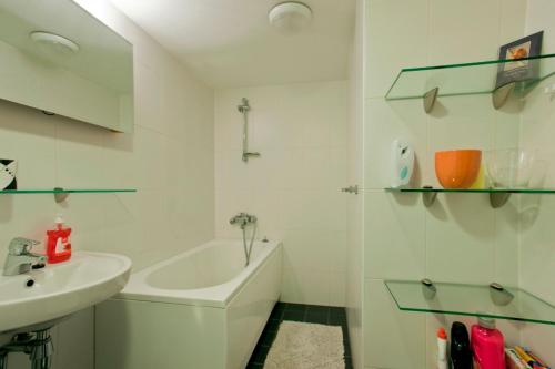 een witte badkamer met een wastafel en een bad bij Tatari Apartment in Tallinn