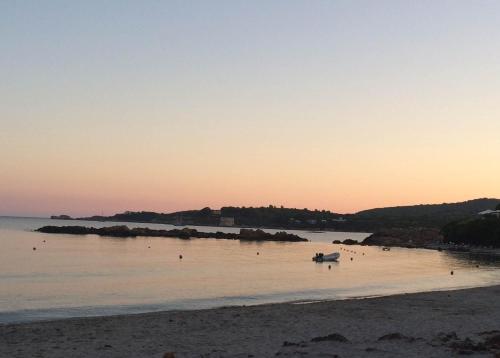 a beach with a boat in the water at sunset at Rosanna House in Bombarde Beach in Alghero