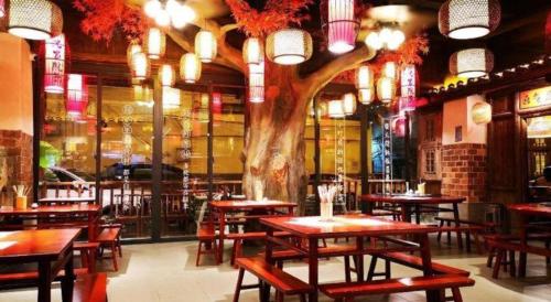 ein Restaurant mit Tischen und einem Baum in der Mitte in der Unterkunft City Comfort Inn Huizhou Huiyang High-speed Railway Station in Huizhou