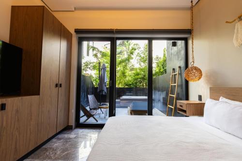 a bedroom with a bed and a sliding glass door at Tulum Escape - Private Hot Tub, Steps to Free Beach in Tulum
