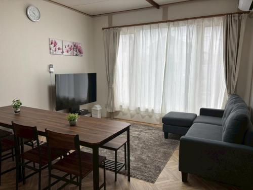 a living room with a table and a couch at 釧路駅近く貸切戸建 ベッドルーム4 シングルベッド9 白金戸建 in Kushiro