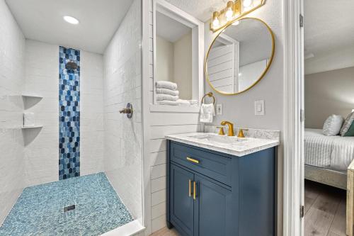 a bathroom with a blue cabinet and a mirror at Honeysuckle - L in Siesta Key