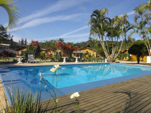 una piscina con una terraza de madera y palmeras en Chalés Villa Bella, en Florianópolis