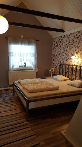 duże łóżko w sypialni z oknem w obiekcie Gärdesgården Lillstugan w mieście Maramö