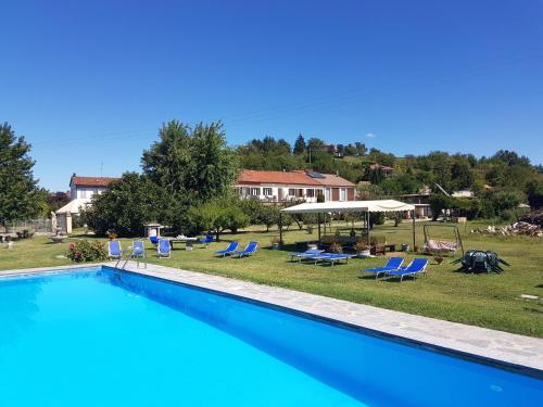 una gran piscina con sillas azules y una casa en La Crota, en Asti