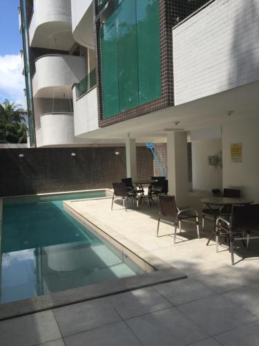 a swimming pool with chairs and a table in a building at Apartamento Capitães de Areia in Ilhéus