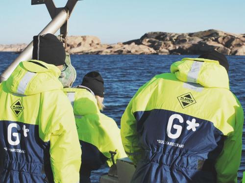 three people in yellow jackets on a boat in the water at Gullmarsstrand Hotell & Konferens in Fiskebäckskil