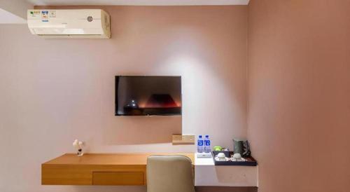 a room with a desk and a tv on the wall at Borrman Hotel Guangzhou Railway Station Yuexiu Park Memorial Hall in Guangzhou
