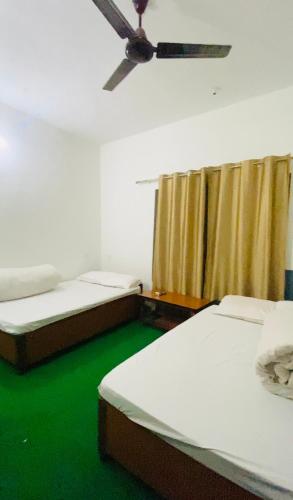 a room with two beds and a ceiling fan at Hotel Bajhang in Bahāsi