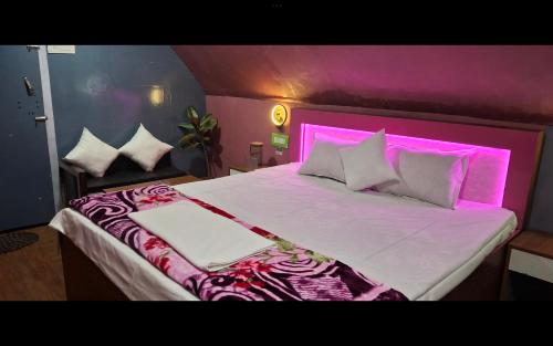 una cama grande con una luz rosa encima en Youon, en Bakkhali