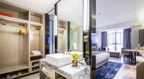 a large bathroom with a sink and a bedroom at Echarm Hotel Hengshui 2nd High School High-speed Railway Station in Hengshui