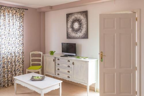 una habitación con una cómoda blanca con un televisor. en Oasis Royal, en Corralejo