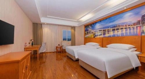 a hotel room with two beds and a large painting on the wall at Vienna Hotel Hubei Enshi Railway Station in Longfengba