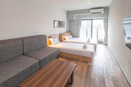 WELLSTAY Osaka Shinimamiya Station في أوساكا: غرفة معيشة بها أريكة وسرير