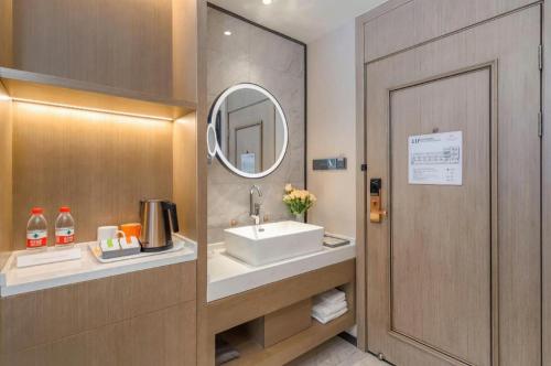ein Badezimmer mit Waschbecken und Spiegel in der Unterkunft Vienna Hotel Tianjin Jinzhong Street in Tianjin