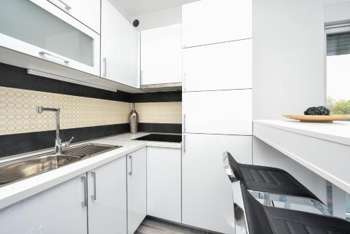 a kitchen with white cabinets and a sink and a chair at Boutique Apartments Blitz in Bibinje