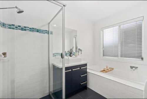 a white bathroom with a shower and a sink at Beachfront Mid Coast Escape in Seaford