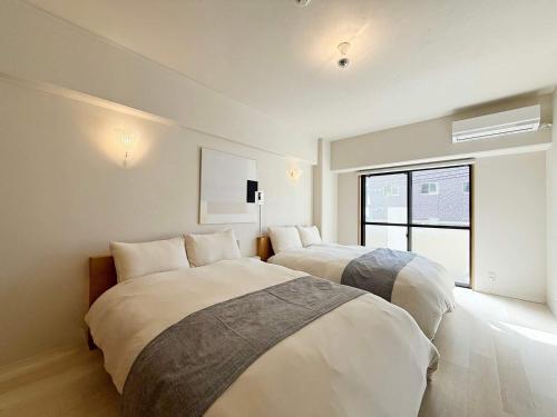 ein Schlafzimmer mit zwei Betten und einem Fenster in der Unterkunft Grandeur by b hotel - Cozy Studio in Perfect Spot Walk to Peace Park in Kami-nagarekawachō