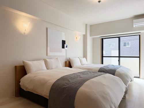 ein Schlafzimmer mit zwei Betten und einem großen Fenster in der Unterkunft Grandeur by b hotel - Cozy Studio in Perfect Spot Walk to Peace Park in Kami-nagarekawachō