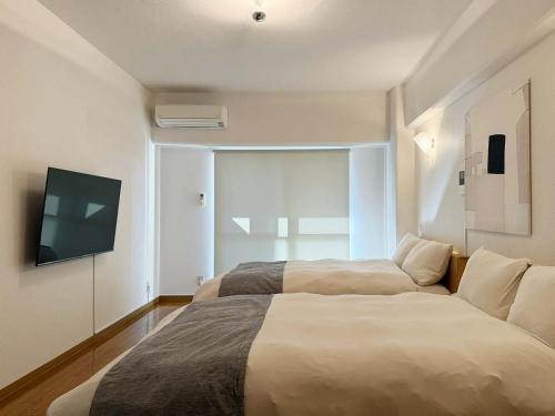 ein Schlafzimmer mit zwei Betten und einem Flachbildfernseher in der Unterkunft Grandeur by b hotel - Riverside Studio Near Peace Park in Kami-nagarekawachō