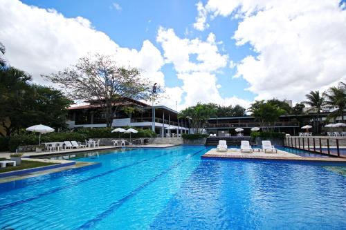 a swimming pool with chairs and a building at Hotel Fazenda Portal de Gravatá in Gravatá