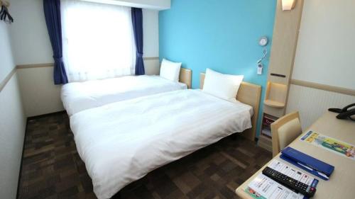 a small room with two beds and a window at Toyoko Inn Tokyo Fuchu Nambu sen Minami tama Ekimae in Inagi