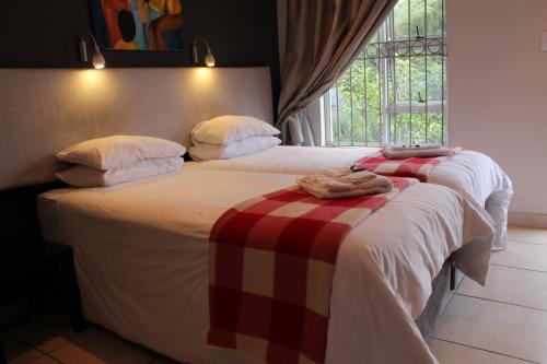 two beds sitting next to a window in a bedroom at 3 Liebeloft Guest House in Edenvale