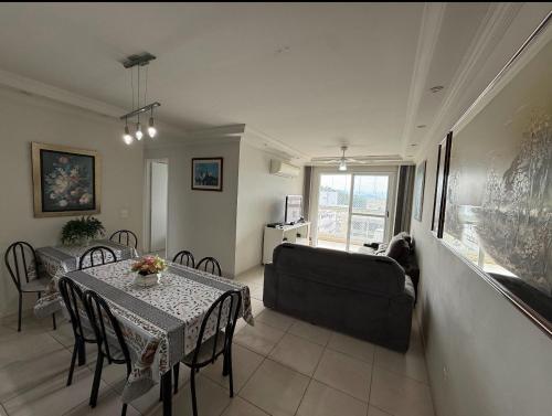 a living room with a table and a couch at Ap 3 qtos 2vg gar cob Twice Guaruja in Guarujá