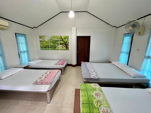 una habitación con tres camas y una ventana en บ้านสวนบรรจงอักษร Bansuan Banjong Akkson, en Ban Chek
