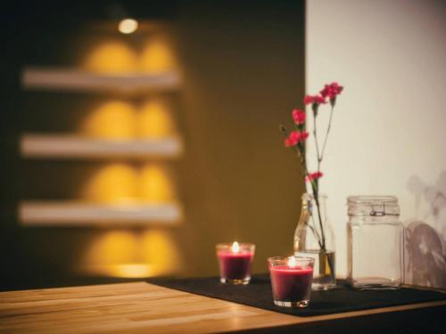 a table with two glasses and a vase with flowers at Apartament Focha 26 in Bydgoszcz