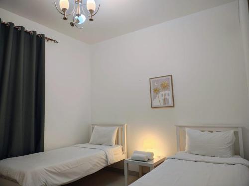 - deux lits jumeaux dans une chambre avec un lustre dans l'établissement Sifa Oasis, à Mascate