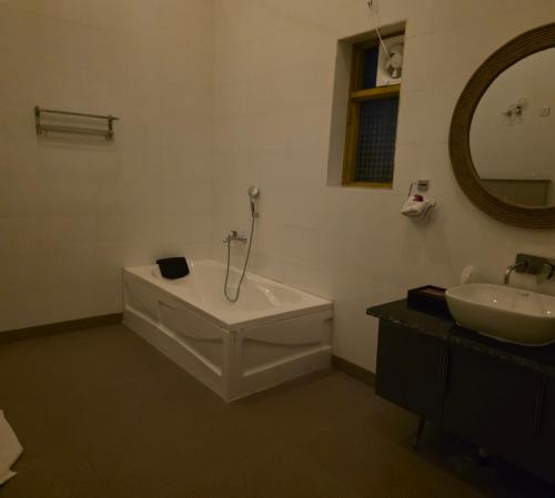ein Badezimmer mit Badewanne, Waschbecken und Spiegel in der Unterkunft Nature lover resort villas in Sonīpat