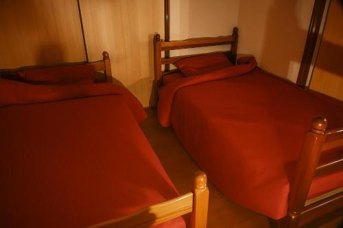 two beds in a room with red sheets on them at ご当地ラーメン食べ放題 "The RAMEN HOTEL" -京都嵐山- in Kyoto
