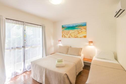 a bedroom with two beds and a window at Pousada Borboleta in Morro de São Paulo
