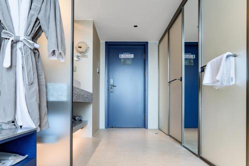 a bathroom with a blue door and a mirror at Chenfeng Hotel Wuhan Baishazhou Longhu Tianjie Branch in Wuhan