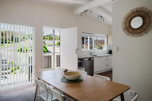 a kitchen and dining room with a wooden table and chairs at Medona - Narrawallee Beach House in Narrawallee
