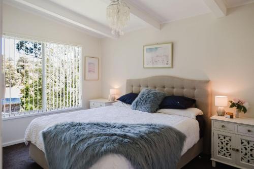 a bedroom with a large bed and a window at Medona - Narrawallee Beach House in Narrawallee