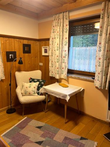 ein Wohnzimmer mit einem Stuhl, einem Tisch und einem Fenster in der Unterkunft Apartement 1 Zur alten Press in Jennersdorf