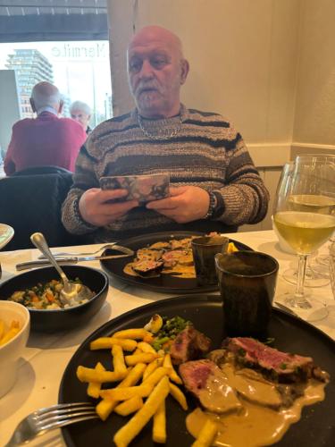 a man sitting at a table with a plate of food at Micheline's plekje in Ostend