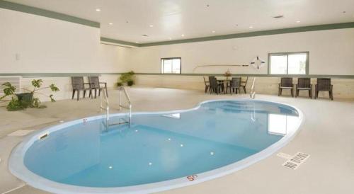 a large swimming pool in a large room with tables and chairs at Americas Best Value Inn Torrington in Torrington