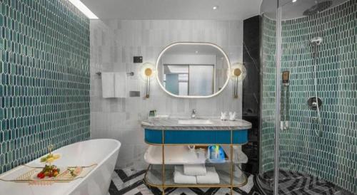 Un baño con bañera, lavabo y espejo. en Hangzhou Blossom Hotel, en Xiaoshan