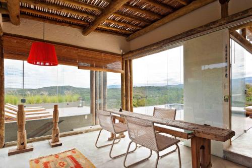 a dining room with a table and chairs and windows at Capim do Mato Pousada & Spa by L'Occitane in Serra do Cipo
