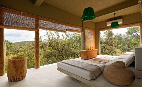 een slaapkamer met een bed en grote ramen bij Capim do Mato Pousada & Spa by L'Occitane in Serra do Cipo