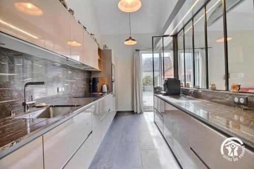 Una cocina grande con encimeras de acero inoxidable y fregadero. en L'oree des mers, en Guidel