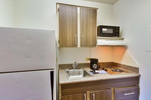 a small kitchen with a sink and a refrigerator at Studio 6-Dallas, TX - Garland - Northeast in Richardson