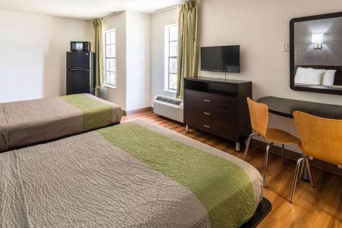 a hotel room with two beds and a flat screen tv at Studio 6-Arlington, TX in Arlington