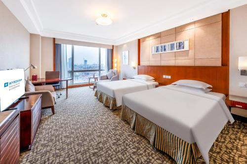 a hotel room with three beds and a flat screen tv at Ramada Beijing North in Changping