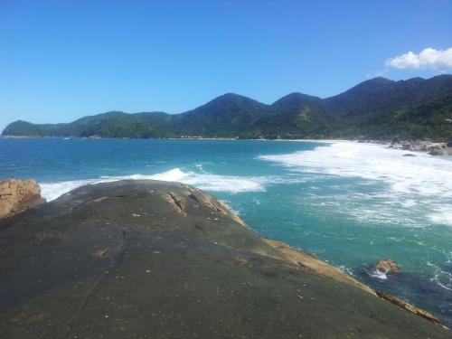 a beach with a large rock in the ocean at Canto do Riacho Suites in Trindade